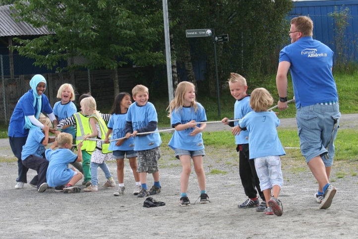 Barn og aktivitetsledere i drakamp med tau