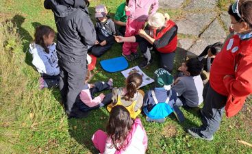 en gruppe mennesker som sitter på bakken utenfor