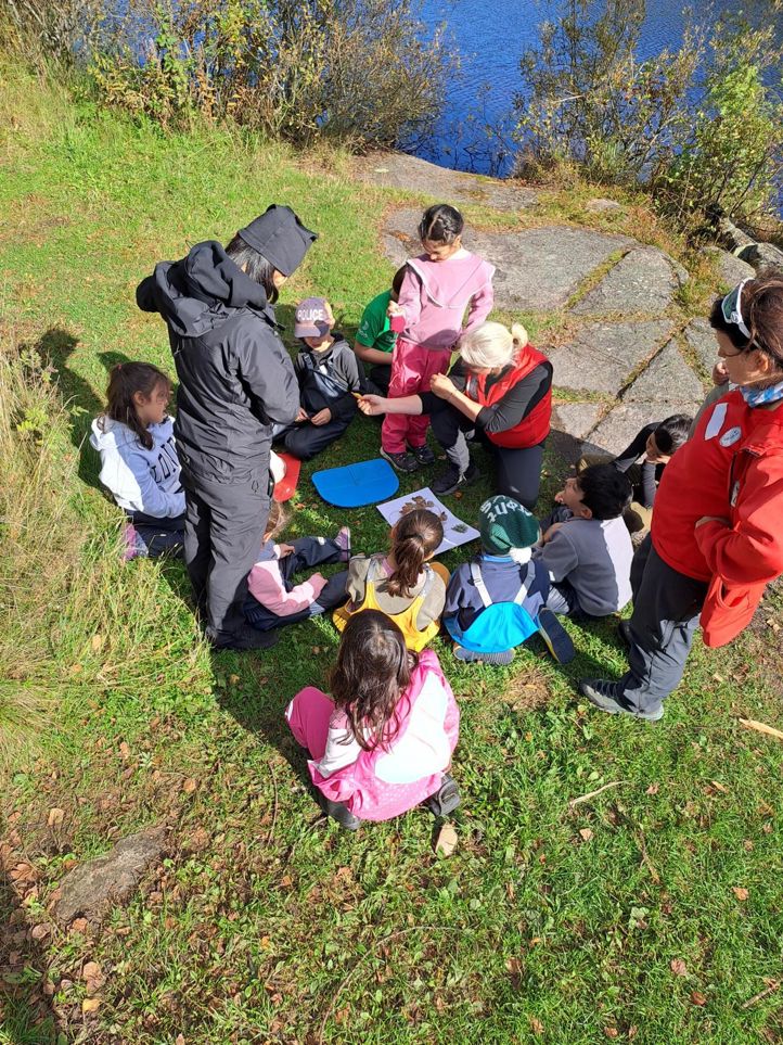 en gruppe mennesker som sitter på bakken utenfor